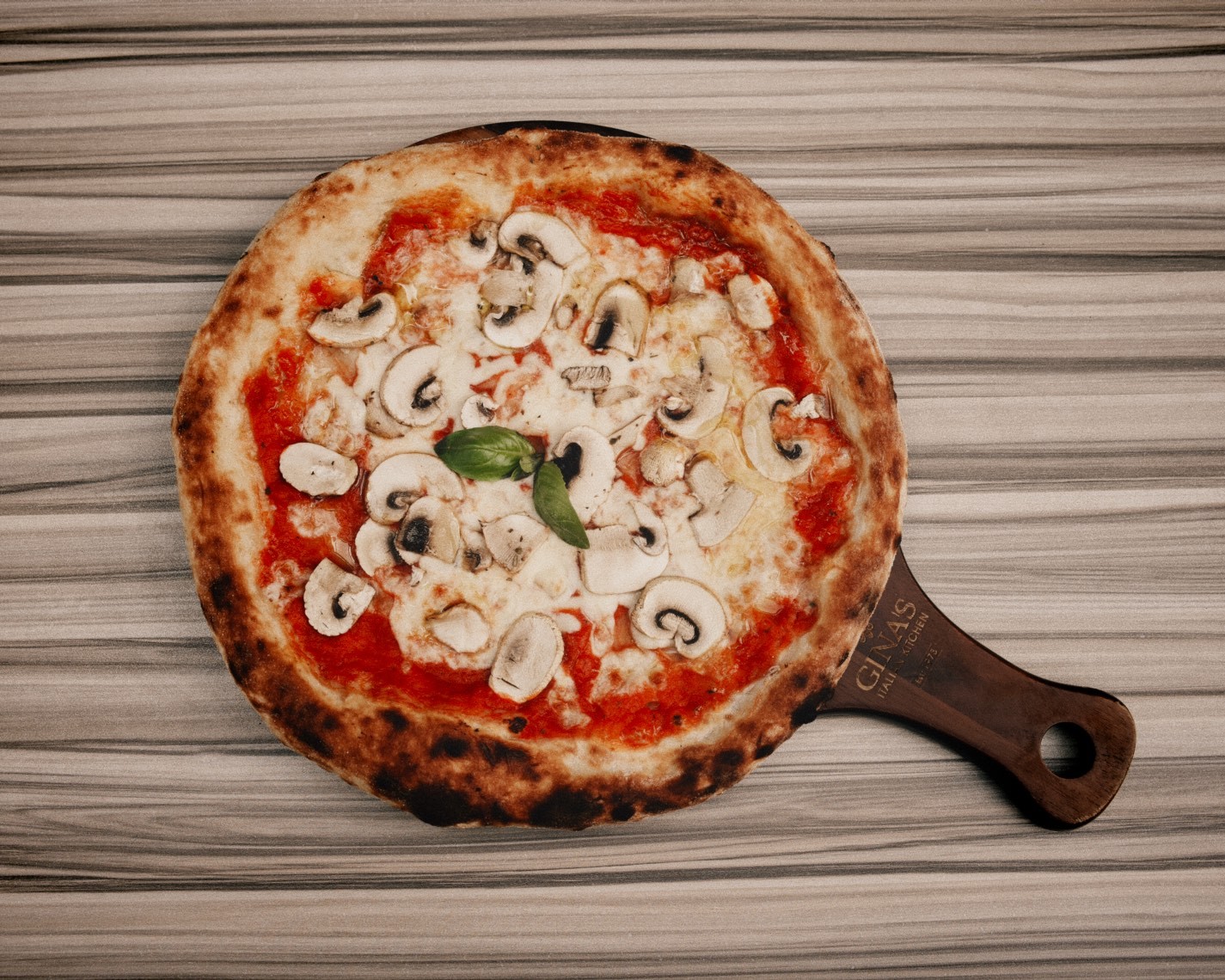 Wood-fire mushroom pizza on a Gina's board