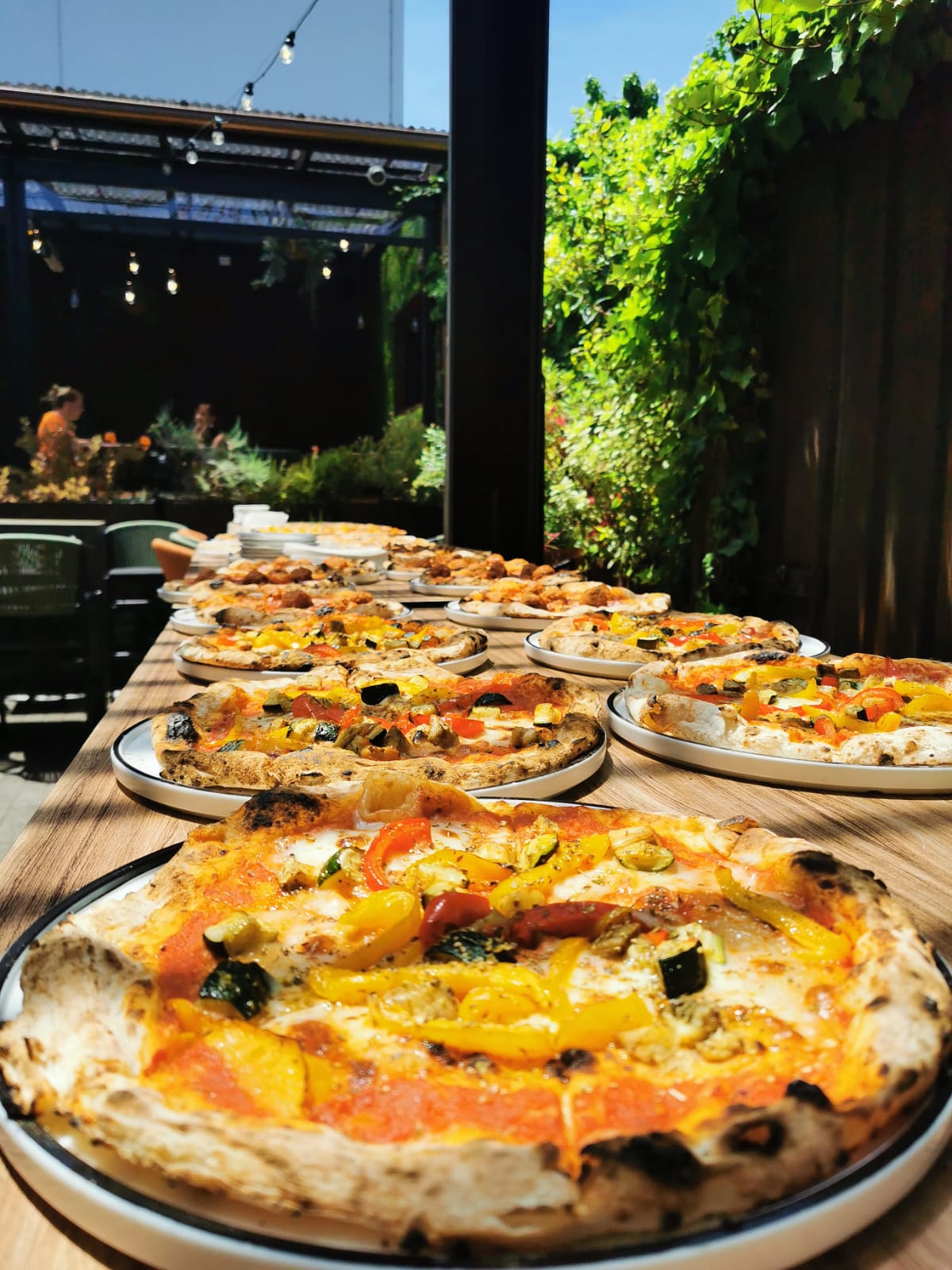 A table lined with wood-fire pizzas for a Christmas function